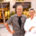 Chef Ana Diaz and a man in a plaid shirt pose outside Pomaterra restaurant on a sunny street.