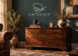 Antique wooden dresser with brass handles against a teal wall, topped with a vintage camera, clock, books, and a ceramic vase with branches.