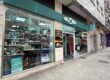Storefront of a shop with teal signage and large glass windows displaying products and promotions in Spanish, including 'COMPRAR VENTA CAMBIA' and 'Vende JOYAS Y ORO'.
