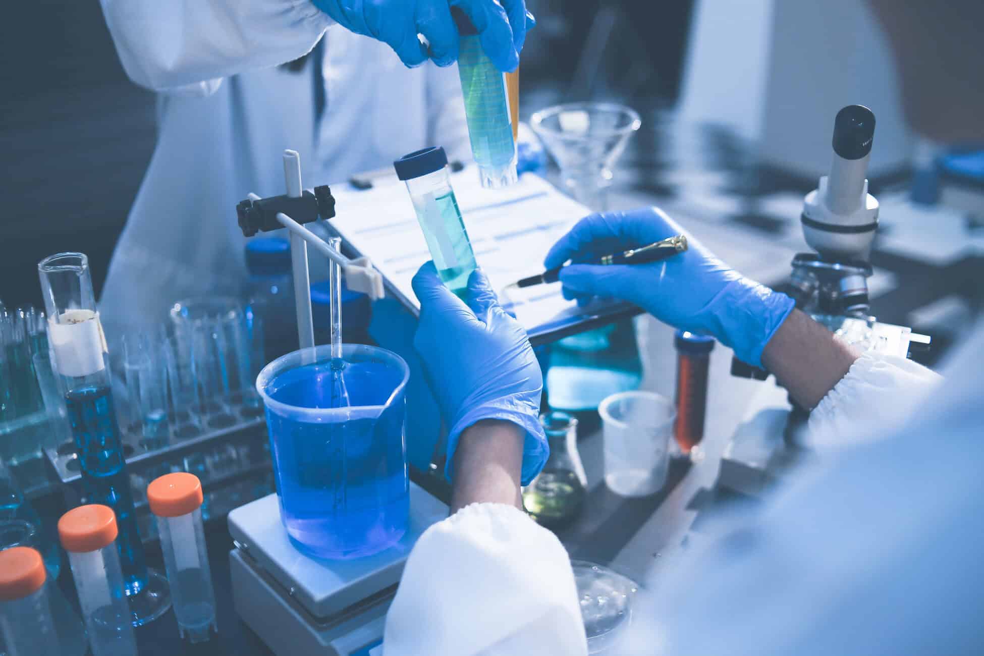 Scientist in blue gloves handling a pipette and test tubes in a lab setting with a blue-tinted background