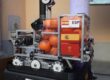 Robotic platform carrying orange balls inside a clear frame, with ESP Spain labels and Spanish flags on the side.