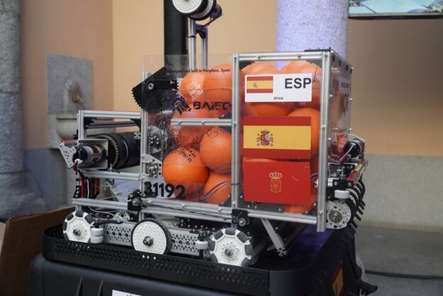 Robotic platform carrying orange balls inside a clear frame, with ESP Spain labels and Spanish flags on the side.