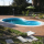 Kidney-shaped in-ground pool in a brick patio, with a green umbrella table set and surrounding garden.