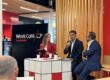 Panel discussion at Work Café Santander with three speakers at a counter, one holding a microphone