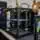 Black 3D printer frame with neon-green clamps on a workbench and spool holders with filament in a lab setting