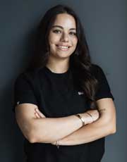 Lydia - Smiling woman with arms crossed against gray background