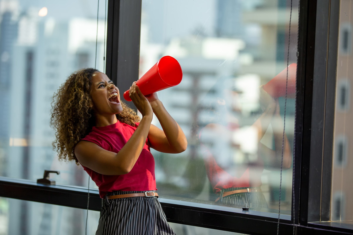 Women Using Her Voice. Shouting On Megaphone with a Cityscape in background.