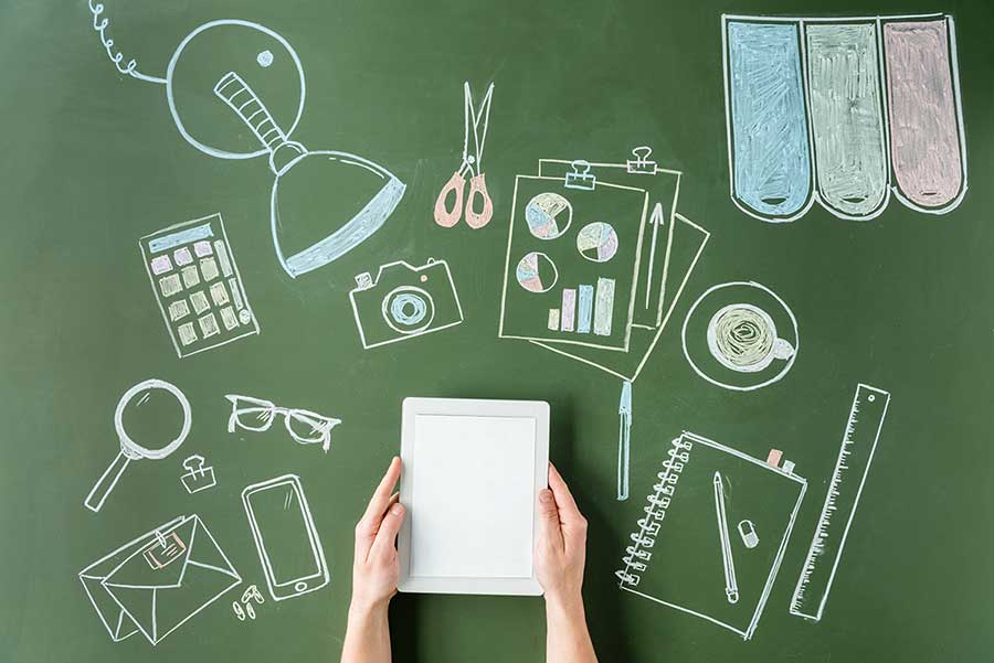 Website Audit. Chalkboard with pictures of a camera scissors, a notebook, a calculator, graphs, and more. Also, a pair of hands holding a tablet.