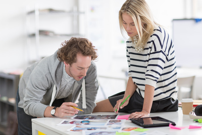 Colleagues Discussing Photographs On Desk In Creative Office