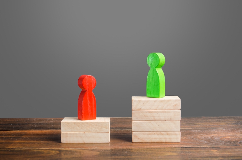 Two figurines, one standing above the other depicting competition