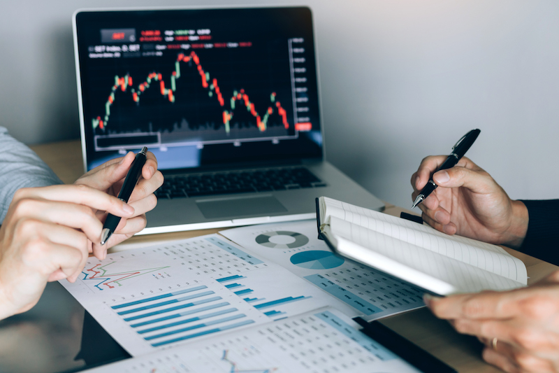 Investors Are Using A Pen To Writing Data For The Company That Is Analyzing The Website Trends of The Upcoming 2023 Year