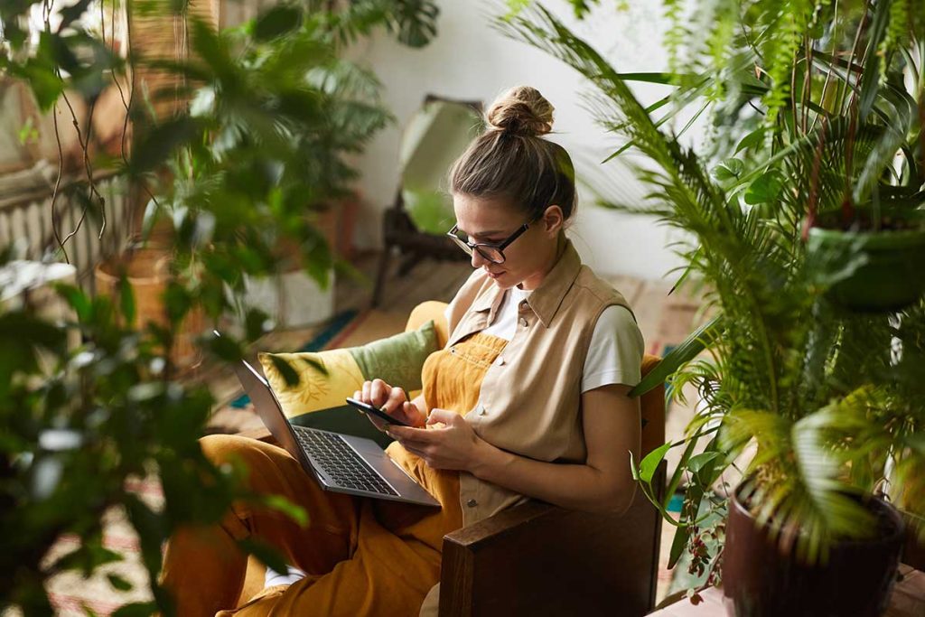 Woman Working On Laptop In Room With Plants