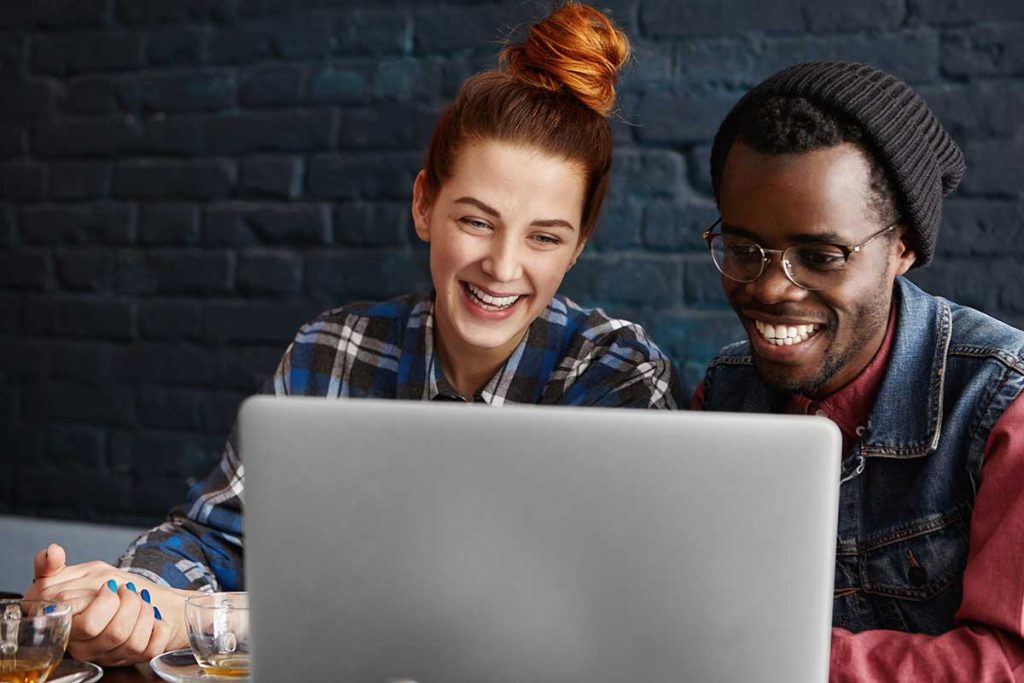 Couple Looking At Computer And Smiling