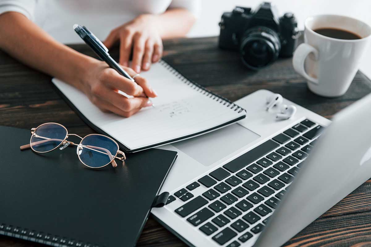 Writing Content On Notebook By Laptop