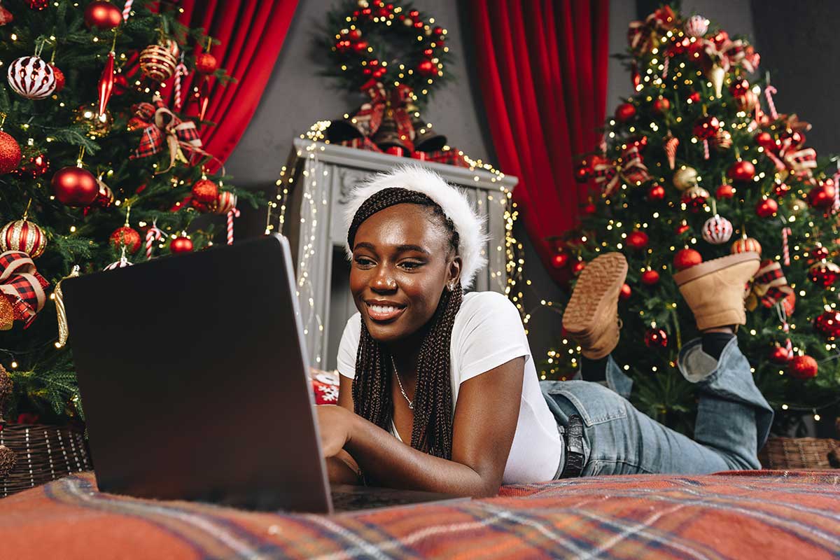 Woman Laying On Floor With Laptop By Christmas Tree