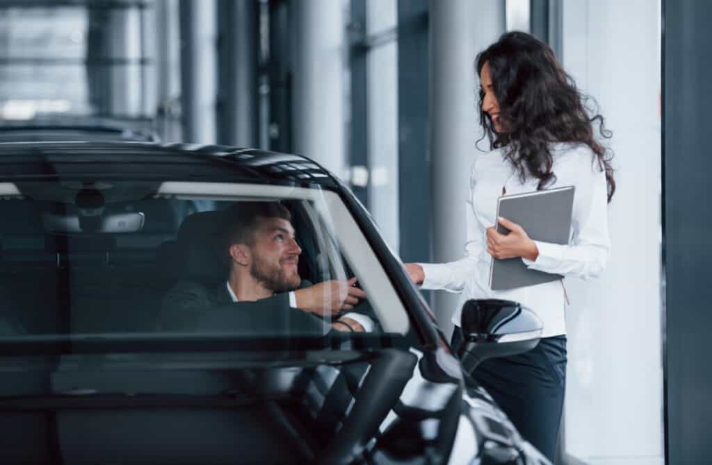 Donna sorridente con cliente in auto, servizio di noleggio auto professionale.