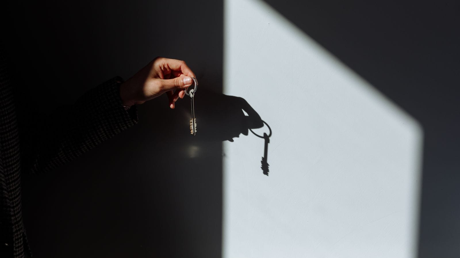 Hand holding a house key casting a shadow on a wall representing a Nevada rental lease early termination