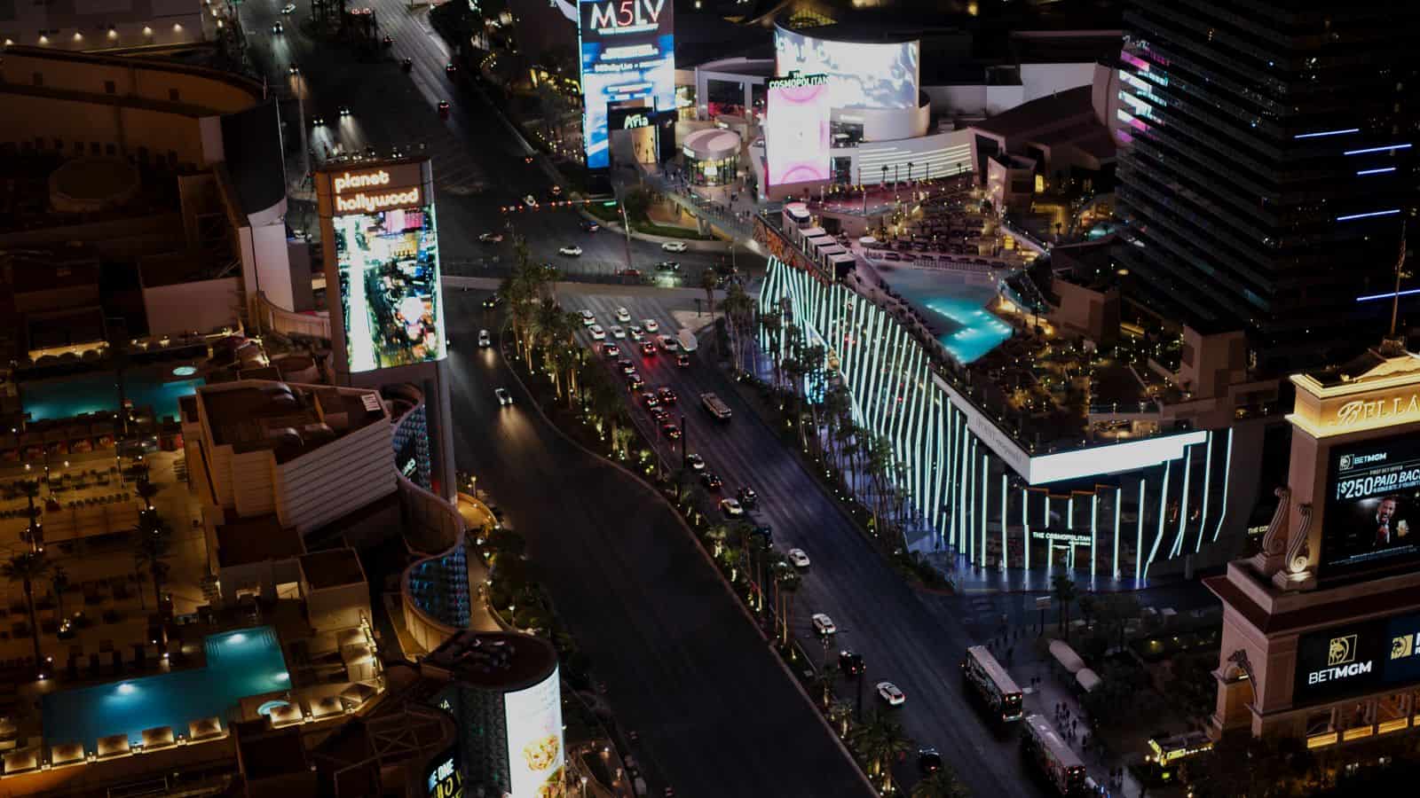 Aerial night view of the Las Vegas Strip with resort towers and city lights stretching across the valley