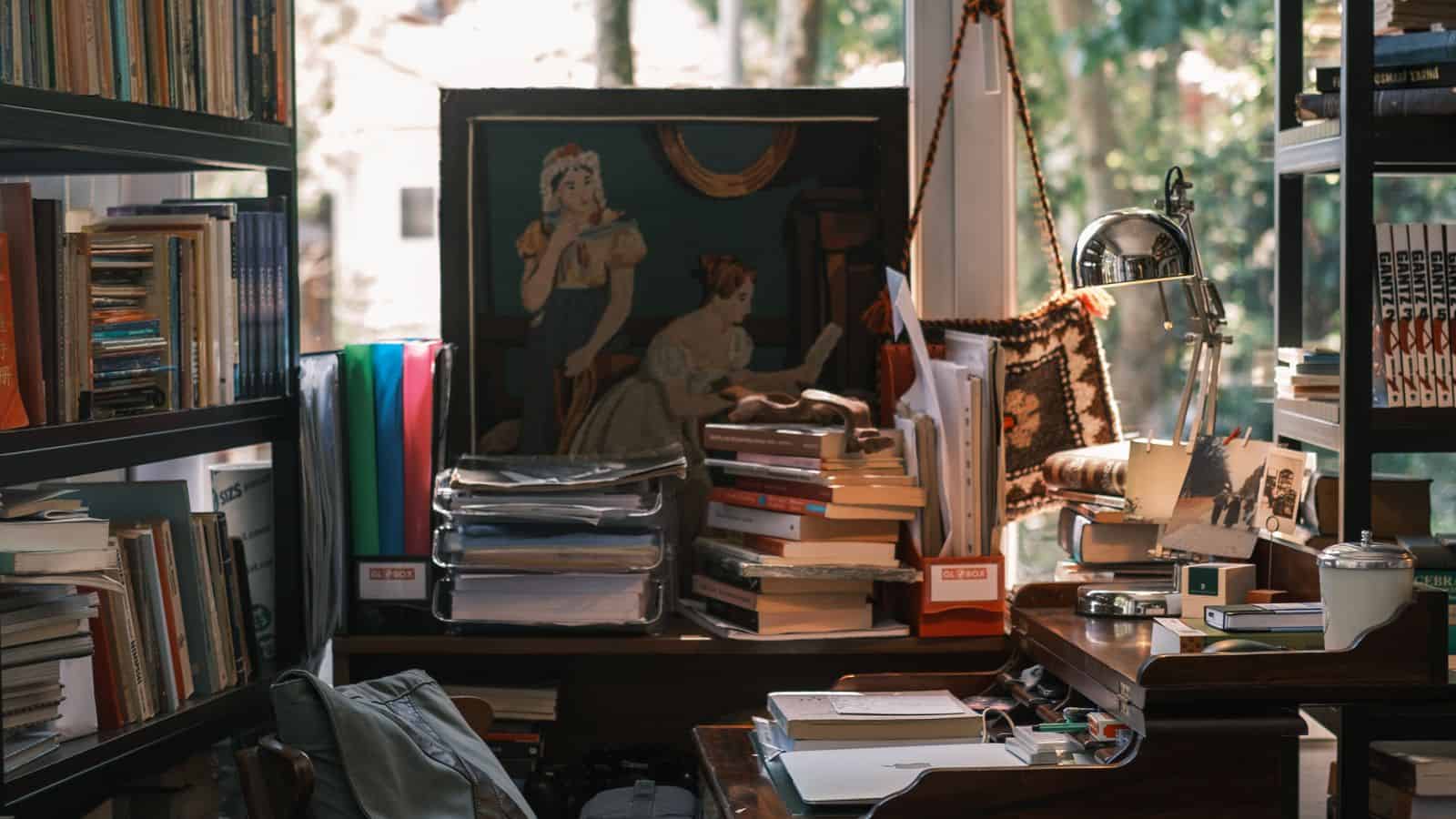 Cluttered Las Vegas rental room filled with stacked books, papers, and belongings near a window