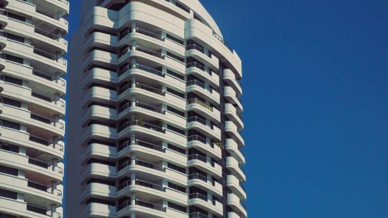 Cream coloured high rise condo tower with balconies against a blue sky