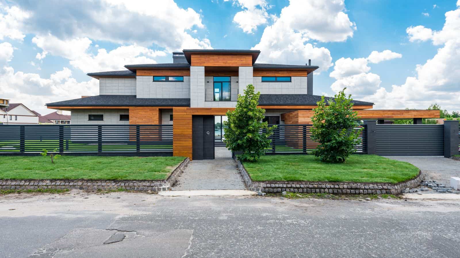 Modern luxury home exterior with dark fence, the type of higher end property where flat fee management often makes sense