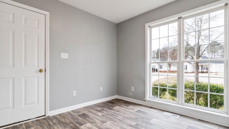 A freshly repainted bedroom wall in a vacant Las Vegas rental with painter's tape and a drop cloth still visible in afte