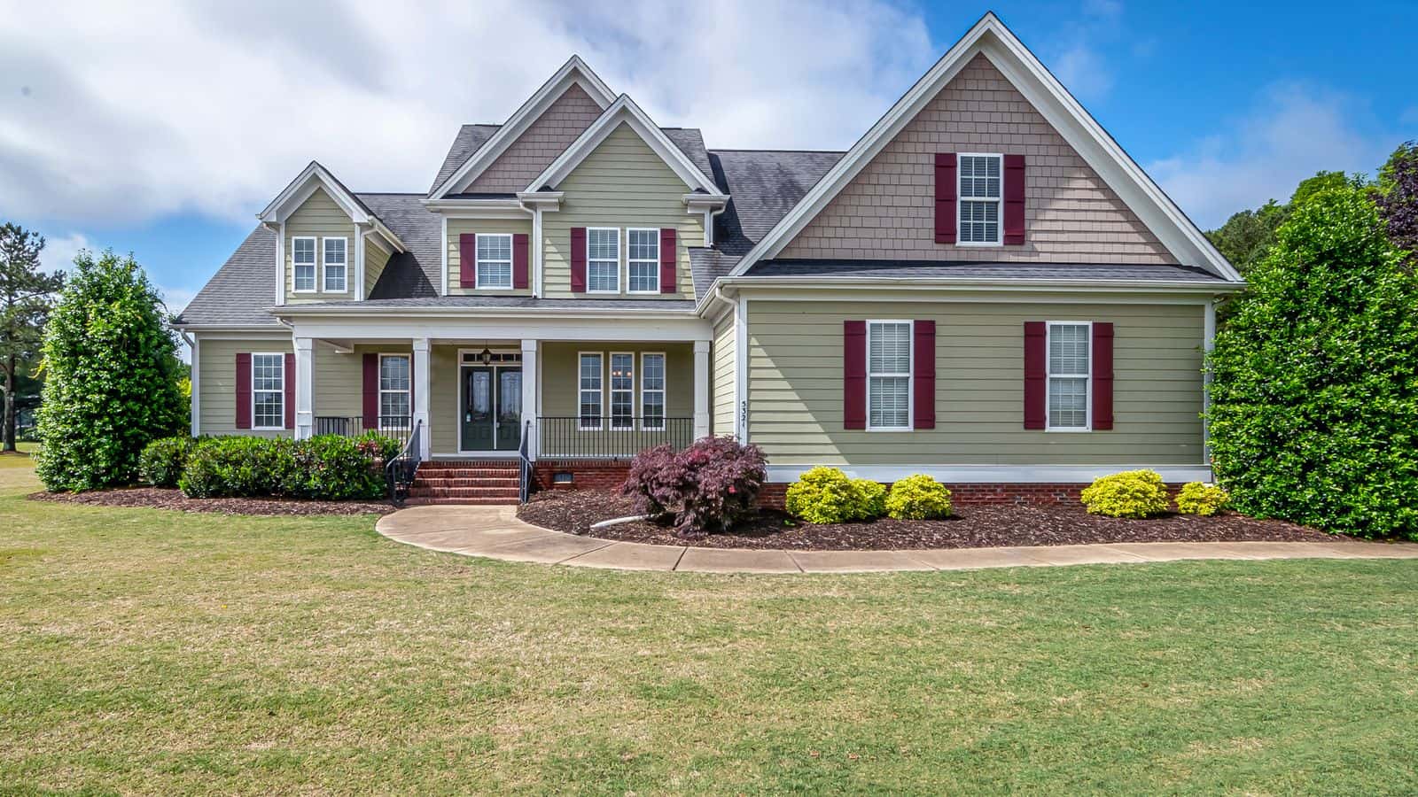 Two-story American suburban house with a green lawn and landscaping