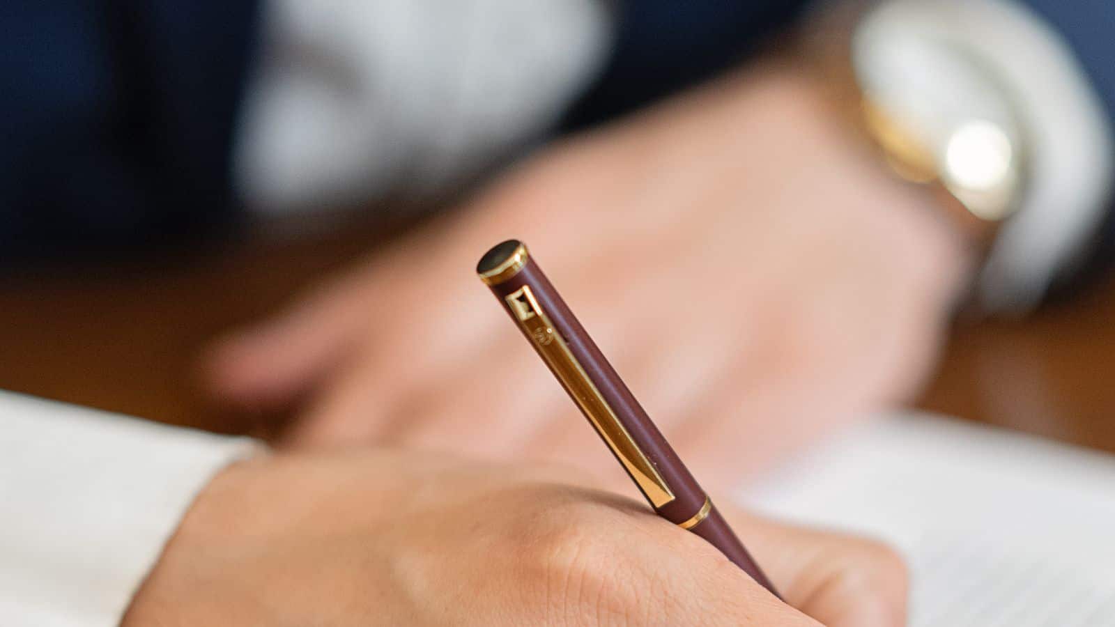 Close up of a hand signing a property management contract document with a pen