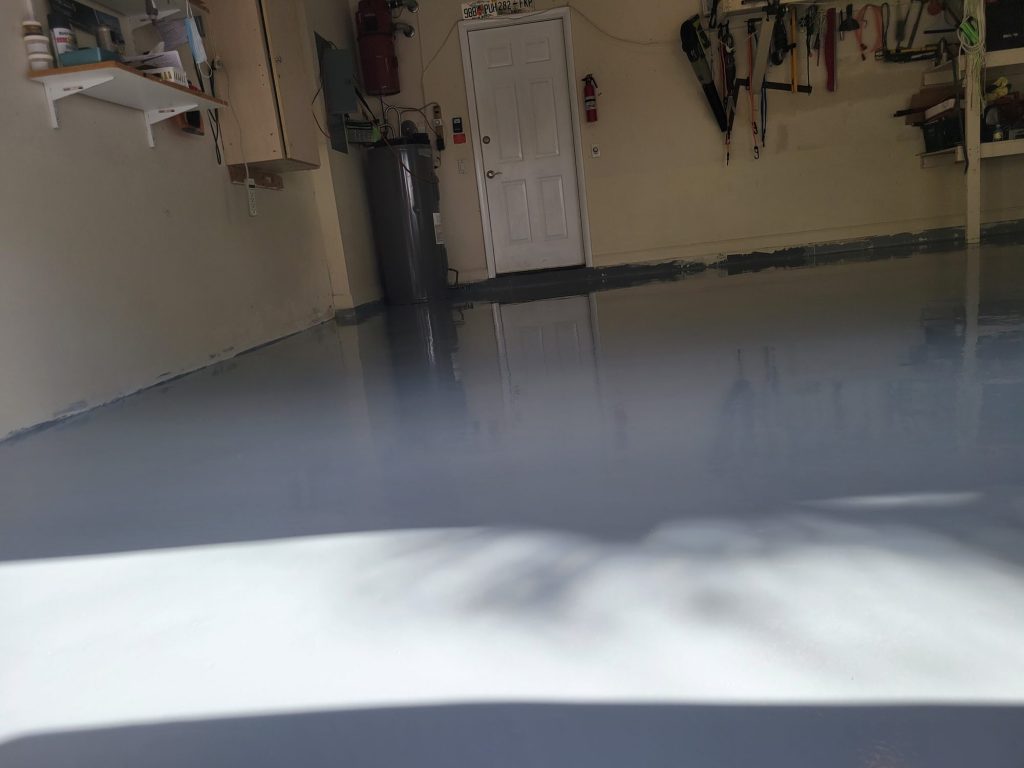 Garage floor coating Wellington: glossy gray epoxy garage floor reflecting light