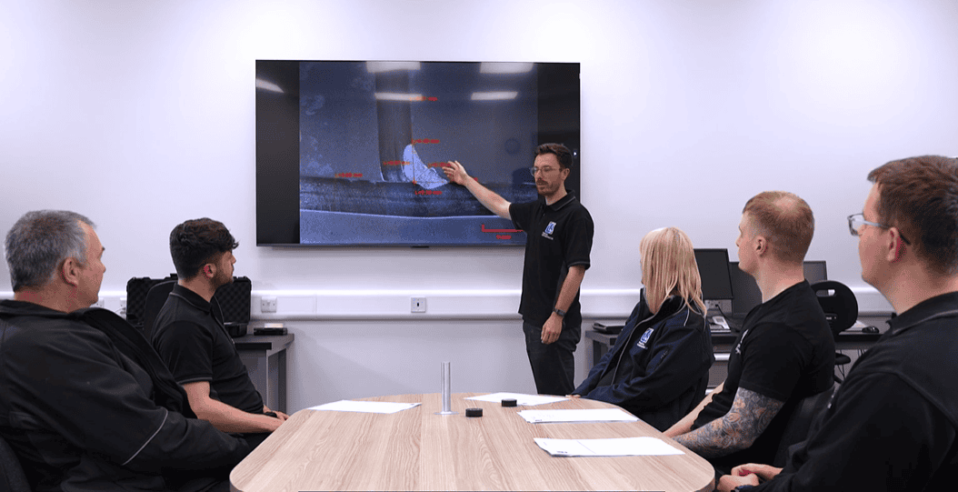 Laboratory technician explains test procedures on a digital screen to staff.