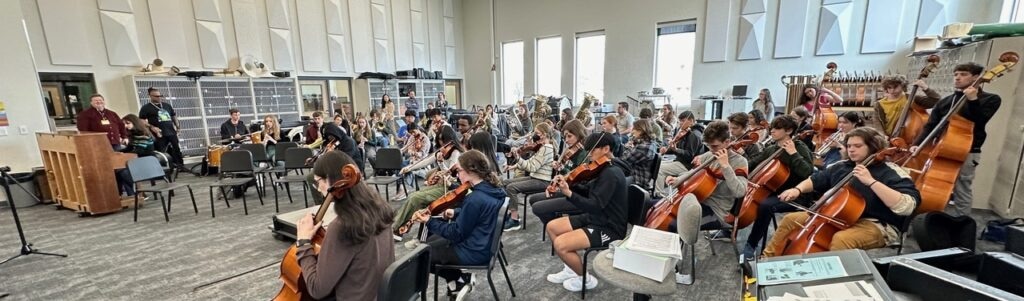 Young musicians playing string instruments in a large rehearsal room for Madison Jazz Society events.