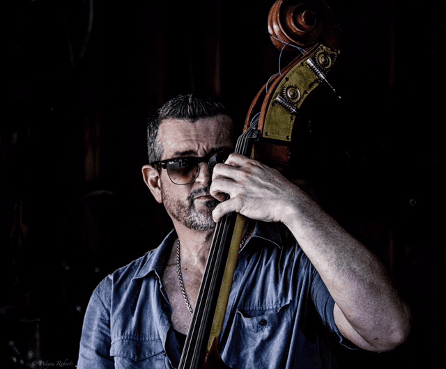 A jazz bassist wearing sunglasses plays double bass at Madison Jazz Society event, showcasing talented jazz musicians and vibrant live music performances.