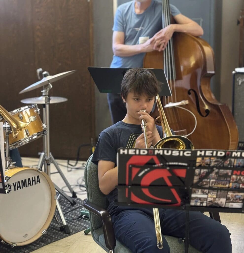 A young musician holds a flute while a bassist plays behind at iGnitE jAzz! 2026