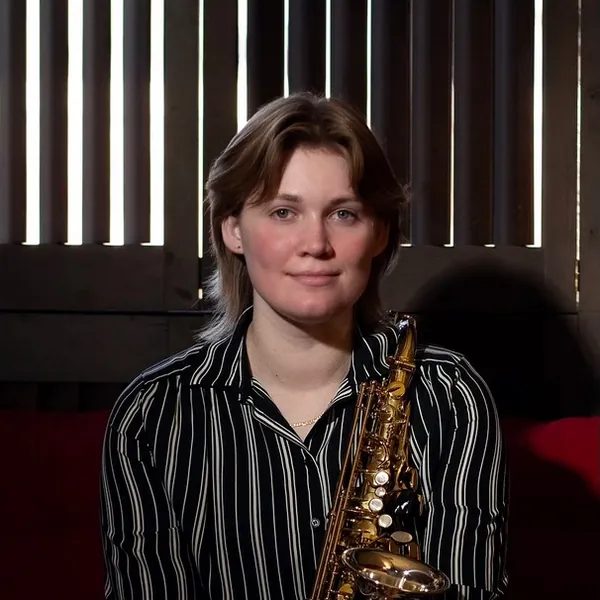 Lucy Croasdale, saxophone instructor at iGnitE jAzz! 2026, seated with an alto saxophone.