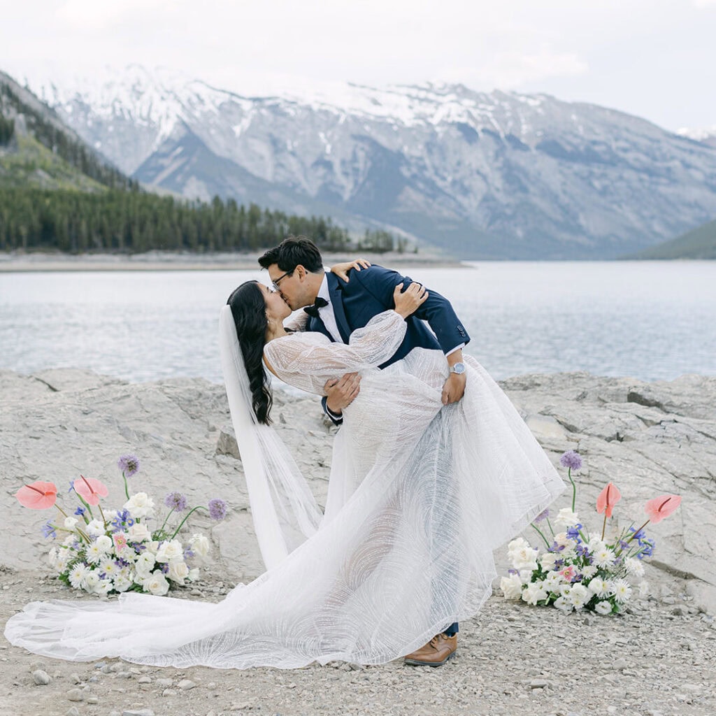 Lake Minnewanka elopement bride and groom embracing with mountain views