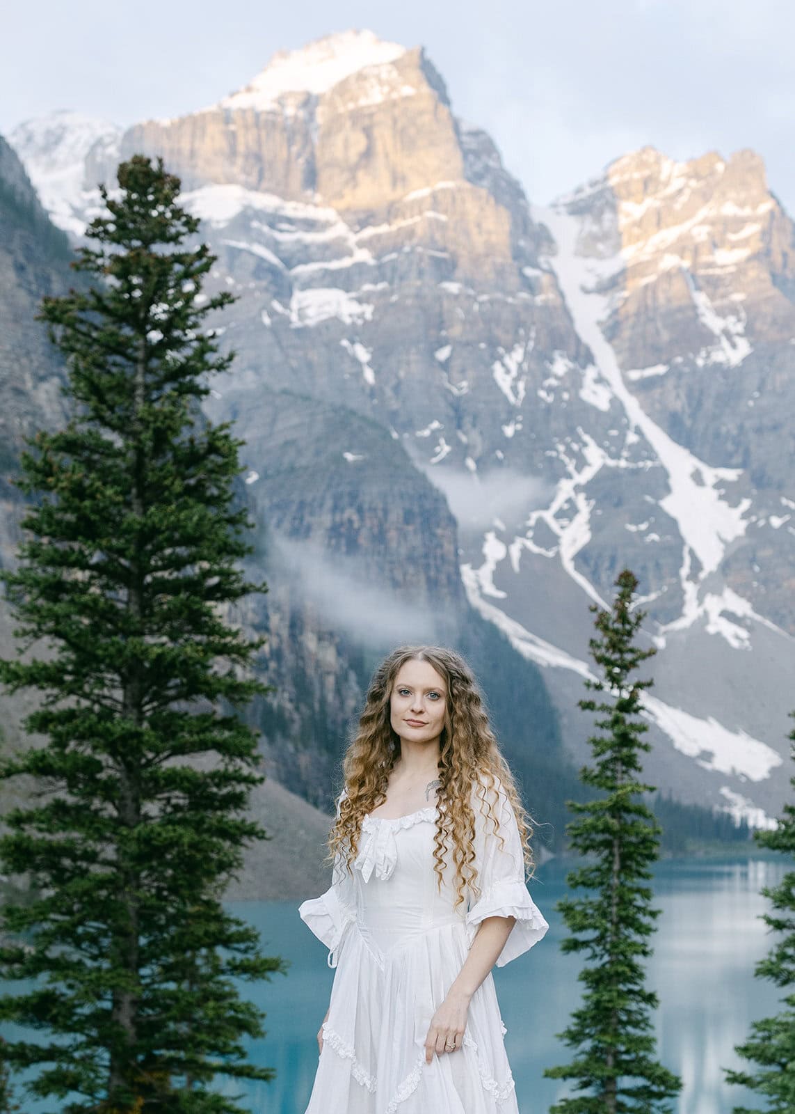Banff elopement photographer photographing a bride with snow-capped peaks in the background