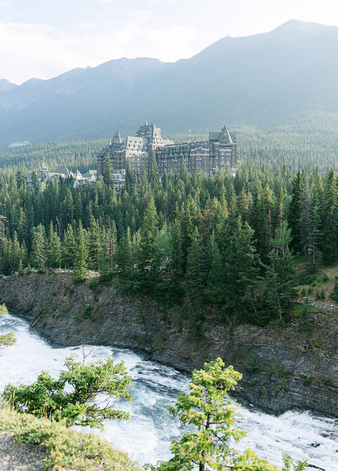 Surprise Corner Banff proposal scene with warm sunset light over the Bow River and Fairmont Banff Springs Hotel