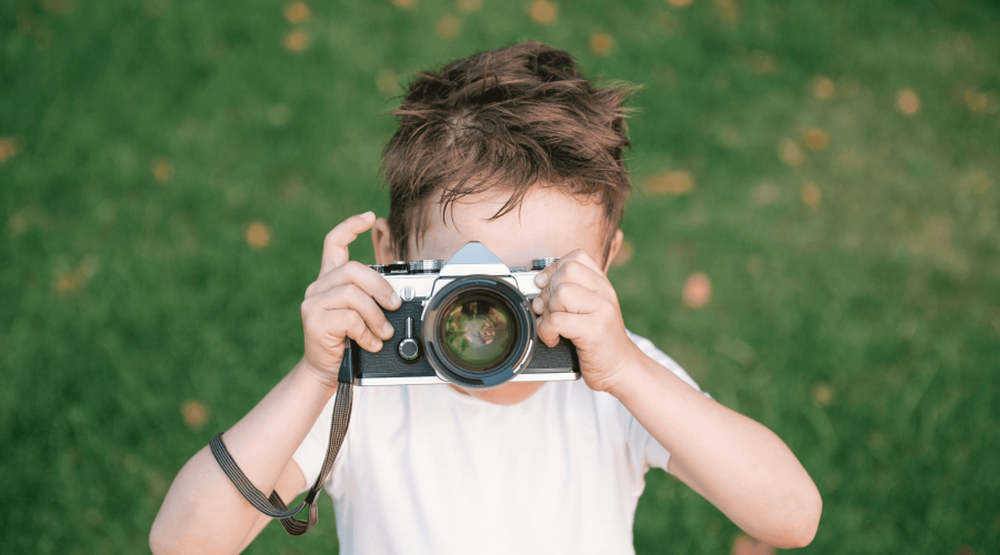 Boy using a vintage camera for documenting Montessori Family Summer Memories
