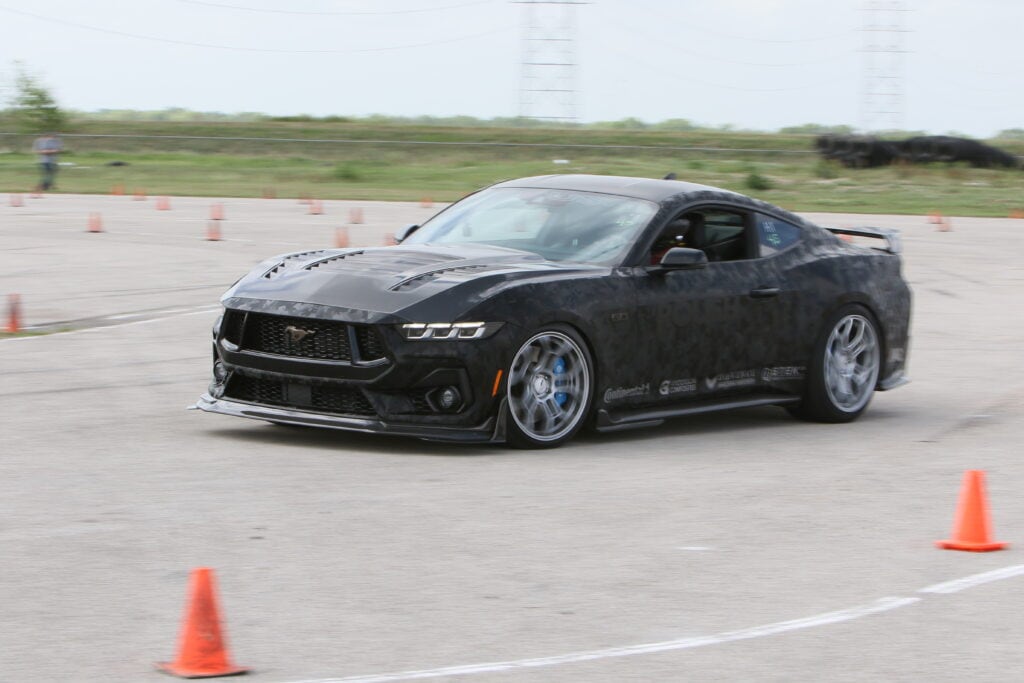 Black Ford Mustang racing on autocross course at Mustang Week.