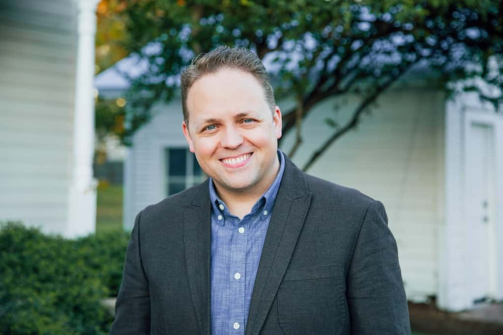 Smiling man in a suit outdoors, representing NLW International leadership.