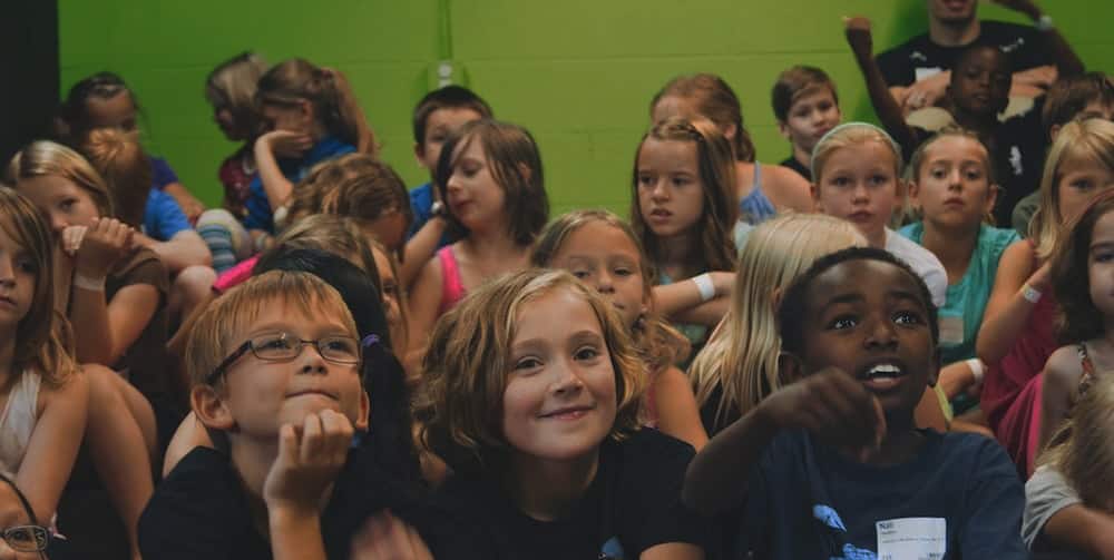 Diverse children engaged in worship at NLW International event.