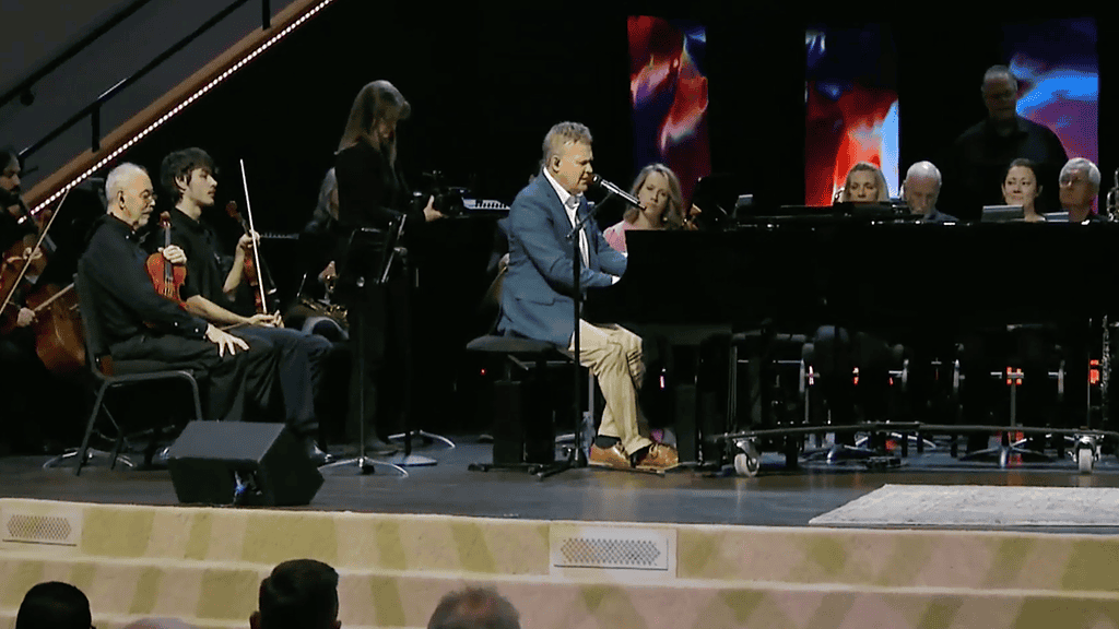 Worship team performing live at NLW International event, featuring singers and musicians on stage.