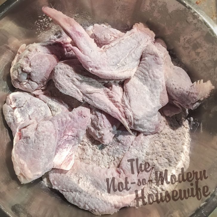 How to Make Delicious Cast Iron Chicken Wings at Home for a Fraction of the Cost | The Not so Modern Housewife Dusting wings in flour - cast iron chicken wings