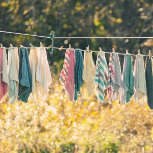 multicolored dishtowels hanging outside in the sun to dry on a clothesline with a line separator