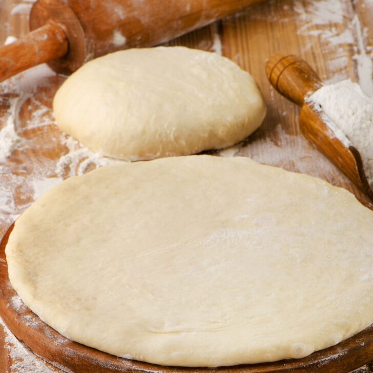 Master the Art of Pizza: Simple Steps to Perfect Easy Pizza Dough | The Not so Modern Housewife homemade pizza crust shaped on cutting board with rolling pin - easy pizza dough