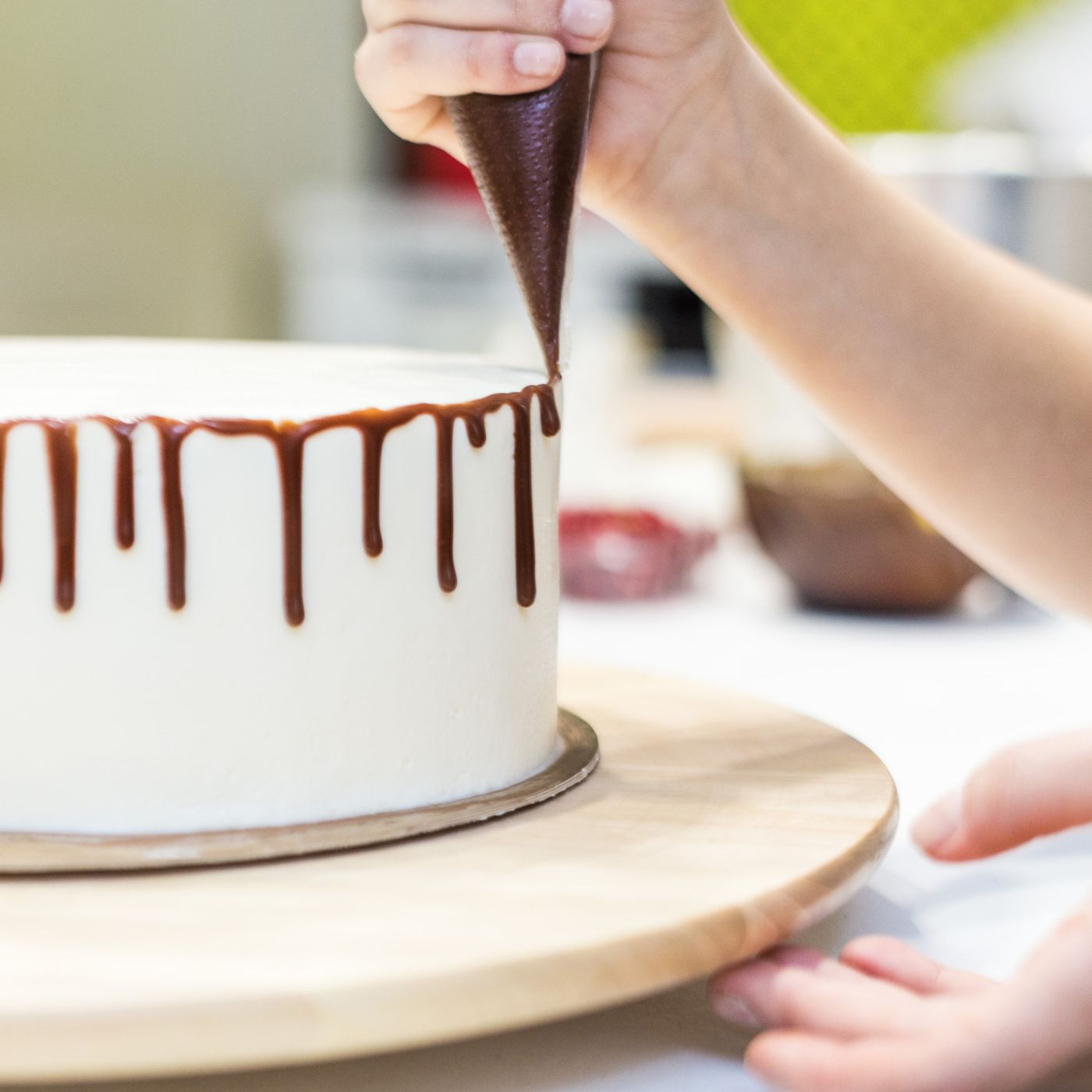 A baker decorates a moist cake made with box cake mix and pudding by piping a rich chocolate ganache drip over smooth buttercream frosting. This easy baking hack creates a soft, bakery-quality cake with minimal effort, perfect for special occasions and homemade desserts.