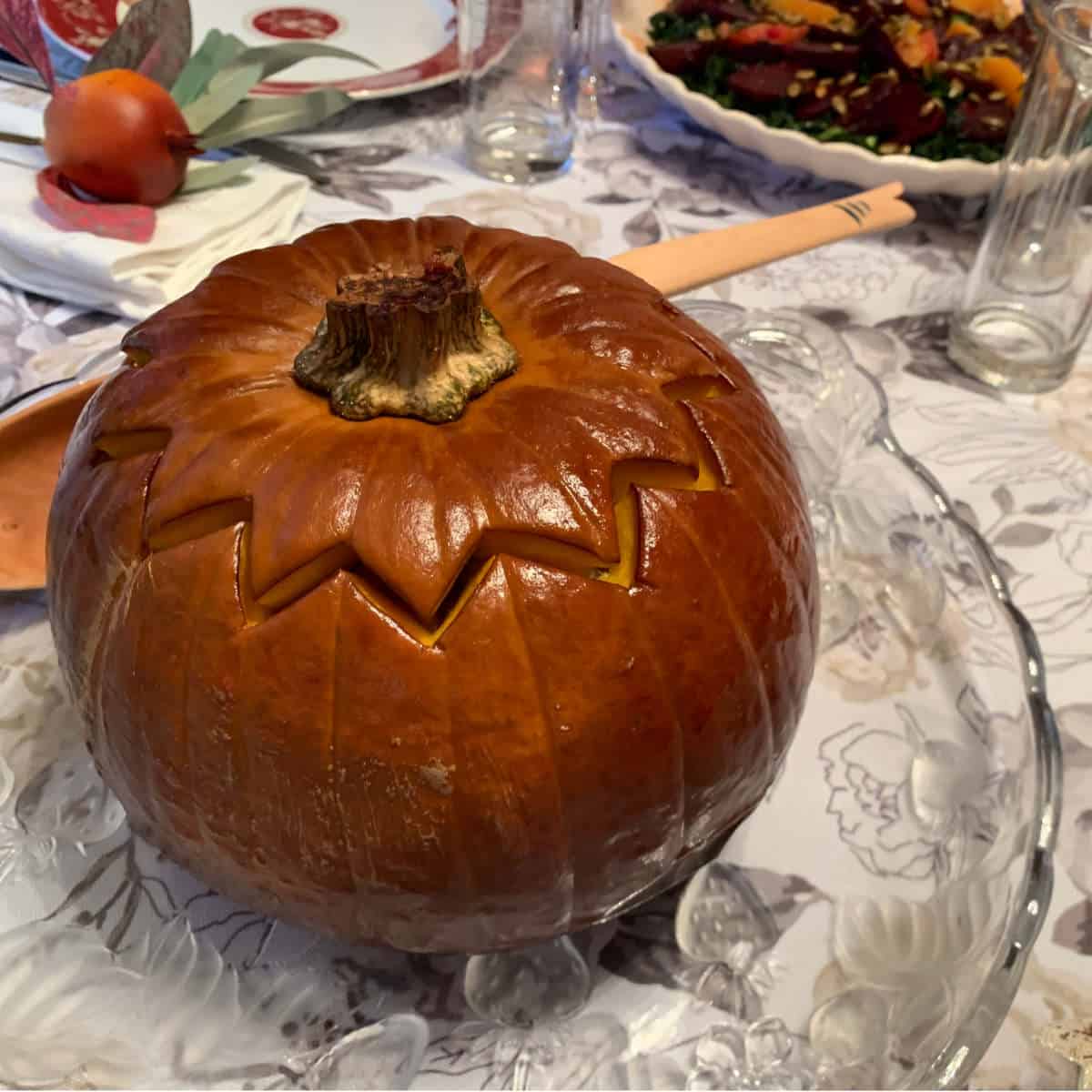 Ghapama, the whole baked and stuffed pumpkin, on a glass platter.