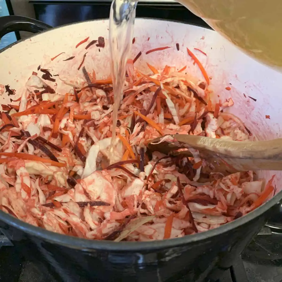 Adding broth to the vegetables.