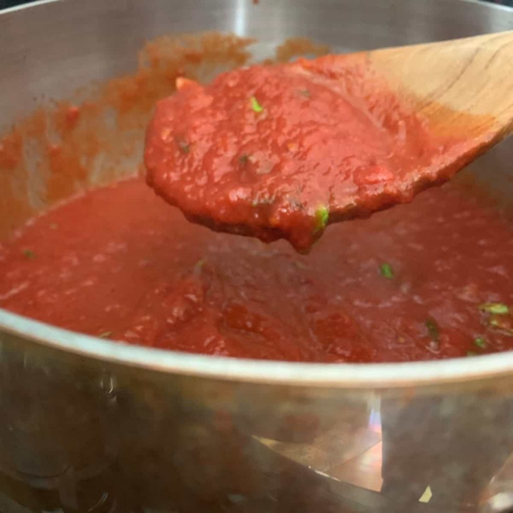 Marinara Sauce in a sauce pan with wooden spoon.