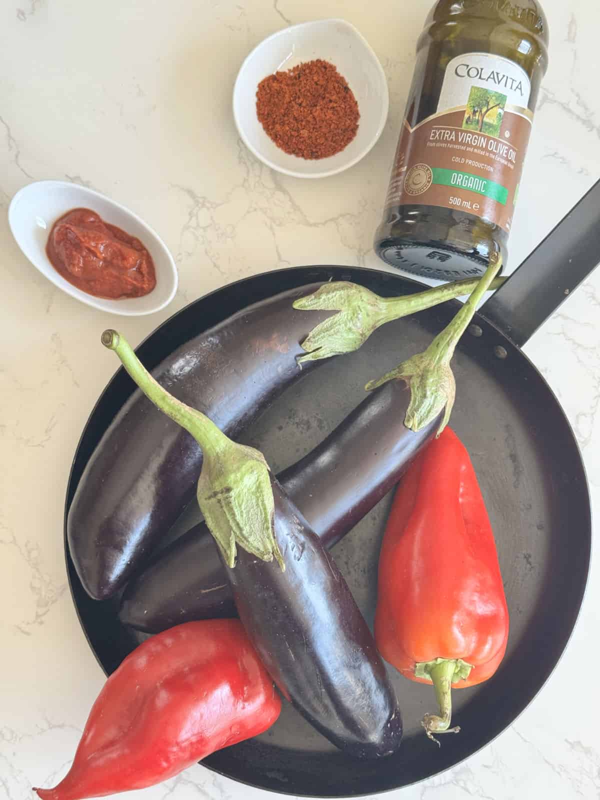 Ingredients for making eggplant caviar; eggplants, red bell peppers, tomato paste, spices and oil.